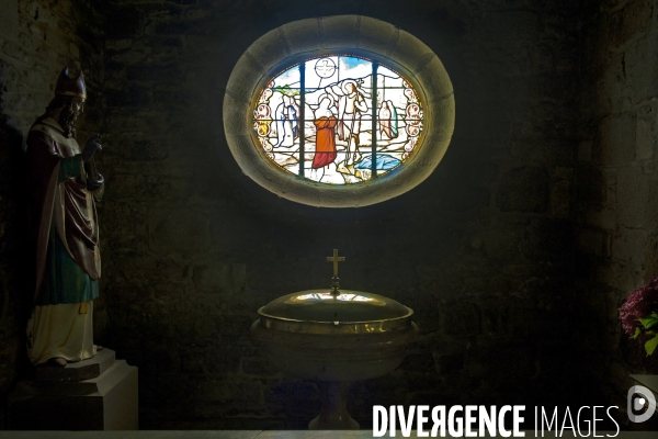 Bretagne.L eglise Notre Dame de Liesse..En oculus, le vitrail pres des fonds baptismaux represente le bapteme de Jesus dans le Jourdain
