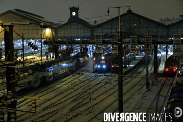 Sous la neige, en soiree, trains au depart de la gare saint Lazare