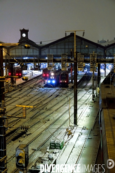 Sous la neige, en soiree, trains au depart de la gare saint Lazare
