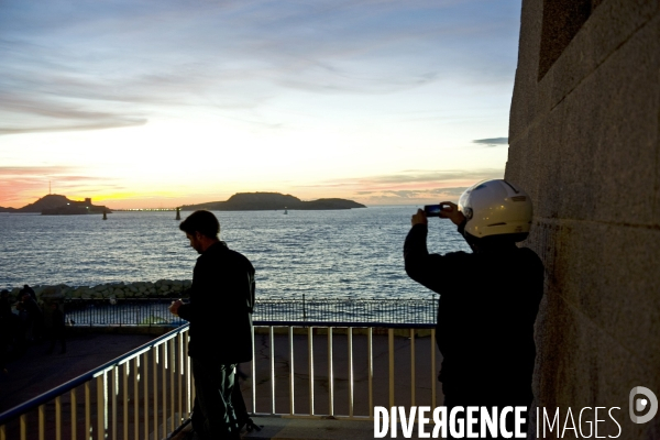 Marseille.De la corniche,un motard photographie le coucher du soleil sur les îles du Frioul.