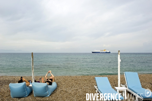 Fin de la saison touristique a Rhodes.Un couple seul sur la plage, chacun occupe par son smartphone et personne dans l  eau