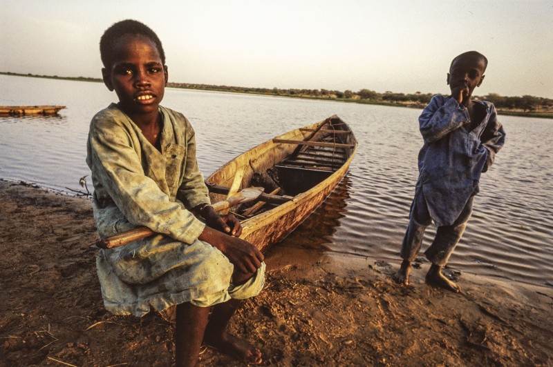 Région du LAC TCHAD: l'avancée de la désertification Un jeune piroguier attendant le client accompagné de son petit frère pour aider à la manoeuvre . 