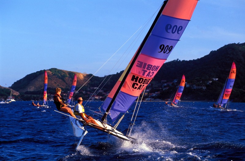 Sport Guadeloupe , Archipel des Saintes , Terre de Haut . Catamaran dans la baie de l ile.  Archipel situé à dix kilomètres au sud de la Guadeloupe, l'archipel des Saintes est un puzzle de neuf îles posées sur la mer des Caraïbes. La baie de l'île de Terre-de-Haut, considérée comme l'une des plus belle du monde, est un terrain de jeu idéal pour s'initier au catamaran, au kayak de mer ou à la plongée sous-marine.