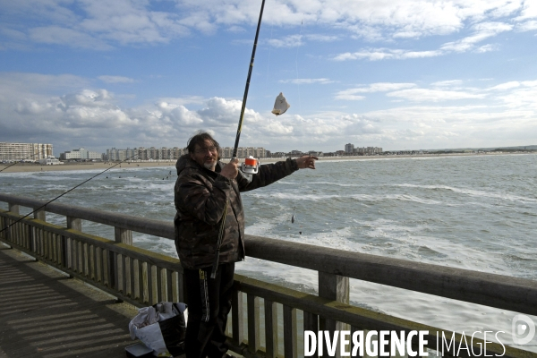 Mai 2016.Un pecheur sur la jetee ramene  un carrelet au bout de sa canne a peche