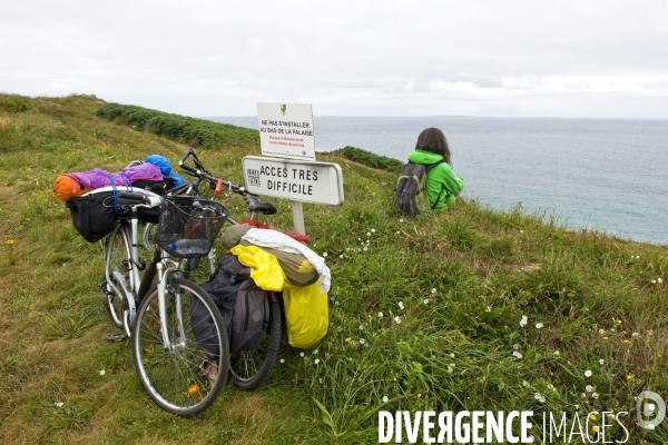 Bretagne.La pointe de Corsen.Cyclotouriste se repose sur la falaise face a la mer d Iroise