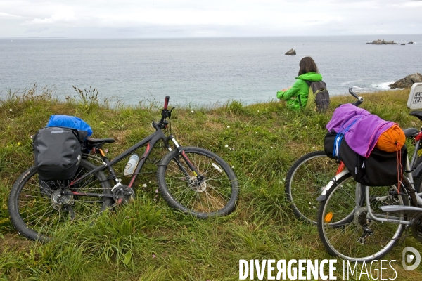 Bretagne.La pointe de Corsen.Cyclotouriste se repose sur la falaise face a la mer d Iroise