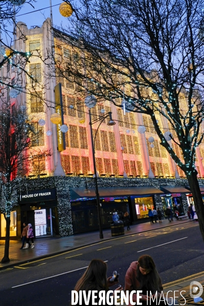 Londres. L une consulte son smartphone, l autre se refait un beaute, deux jeunes femmes sur un banc d Oxford street devant le gand magasin House of Fraser