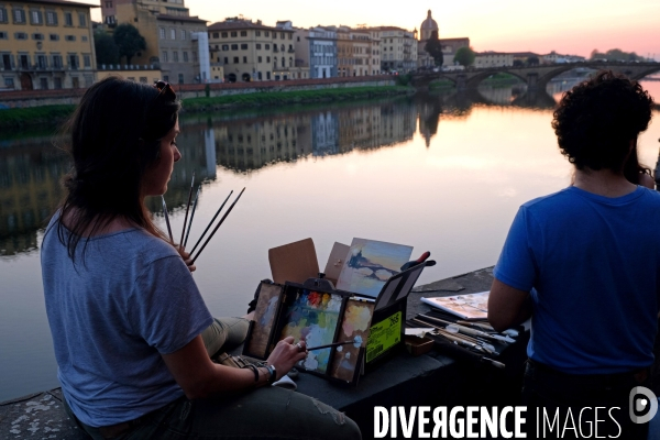 Florence.Au coucher du soleil,une jeune peintre sur les bords de l Arno, acheve un tableau representant le fleuve et le pont  Santa Trinita.