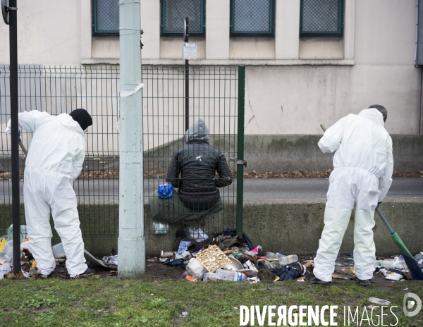 Employés nettoyant une sortie du périphérique derrière un mendiant assis.