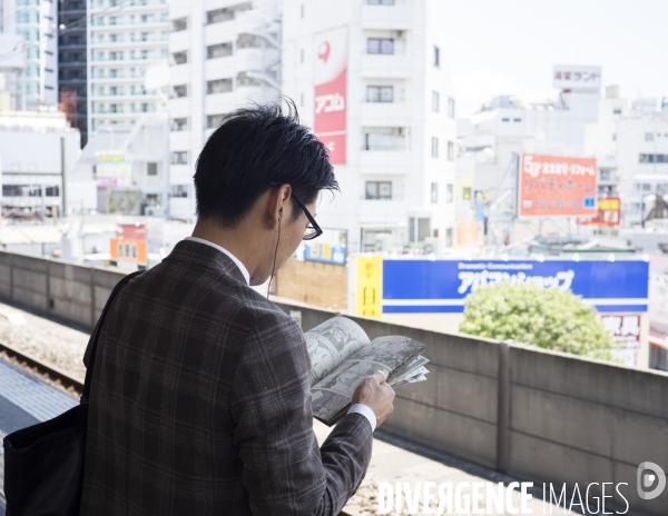 Station de métro Koiwa, un quartier excentré de Tokyo Homme lisant un manga