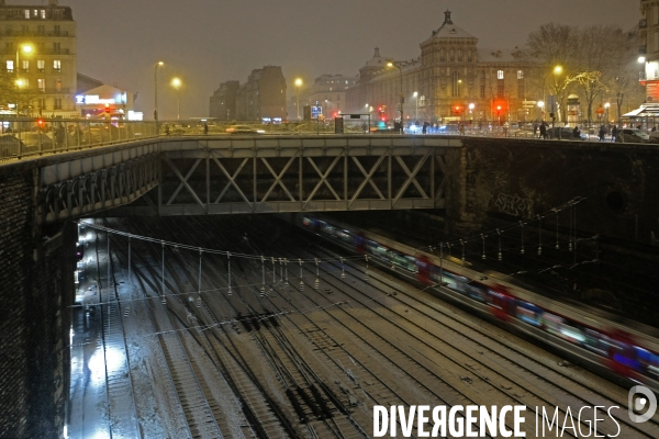 Sous la neige, en soiree, un train de banlieue au  depart de la gare saint Lazare