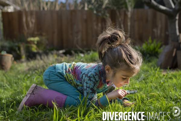 Une petite fille observe la nature dans son jardin avec une loupe