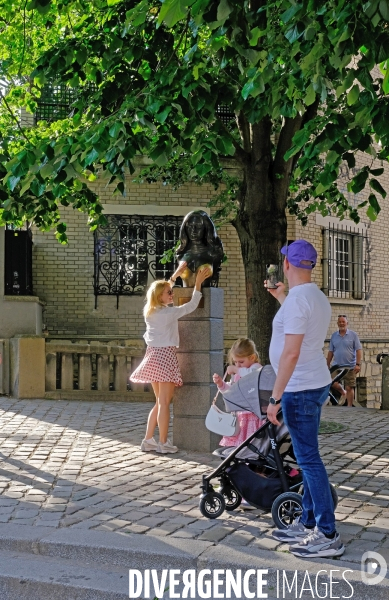 Une femme pose ses mains sur la poitrine du buste de Dalida