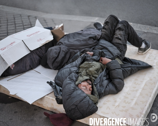 Des hommes endormis sur un matelas devantl Paris Habitat