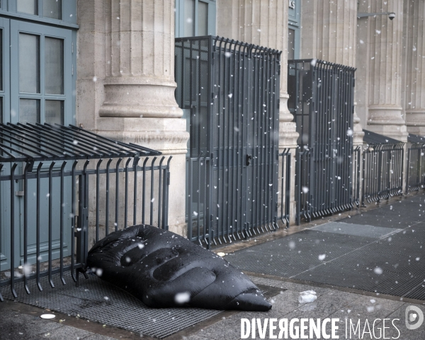 Paris sous la neige.Gare du Nord , Gare du Nord , un SDF couché sous un duvet