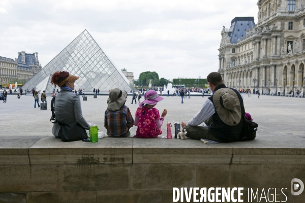 Touristes à Paris.Autour du Louvre.Pic nique d une famille  de touristes dans la cour Napoléon devant la ptramide