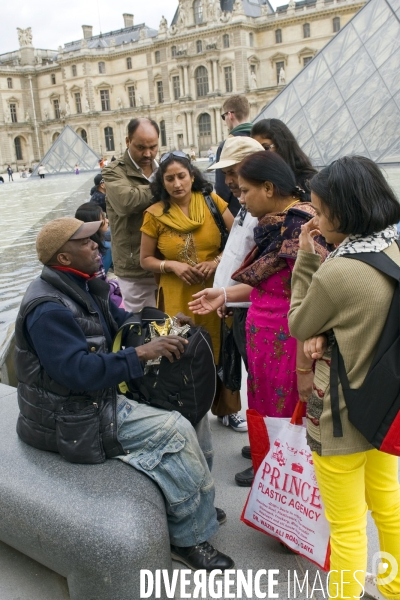 Touristes à Paris.Autour du Louvre.Marchandage entre un vendeur à la sauvette de tours Eiffel et un groupe de touristes