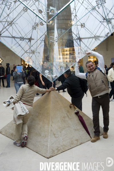 Touristes a la pyramide inversee au Louvre..Seance photo; gestes et poses quasi rituel sous la pointe de la pyramide inversée