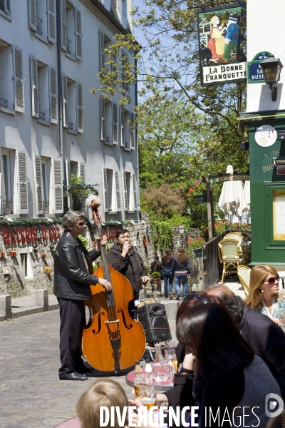 Tourisme a Paris.Autour de la Butte Montmartre.Devant la terrasse d un restaurant des musiciens de rue, une chanteuse et un contrebassiste