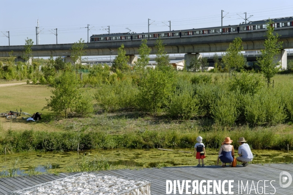 La nature dans la ville -Série 01.Nanterre.Une famille au parc du chemin de l ile regarde un rer  sur un viaduc