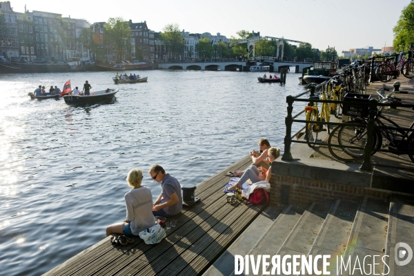 Amsterdam, illustration.Au soleil couchant, detente sur un ponton en bois au bord de la riviere  Amstel