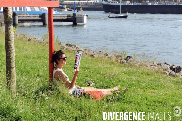 Amsterdam.Jeune fille lisant dans l herbe au soleil sur  la rive nord de la ville de l autre cote de l IJ