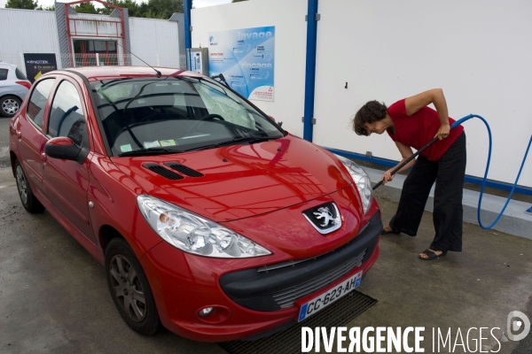 Illustration Septembre 2013.Une femme nettoie sa voiture dans un car wash.