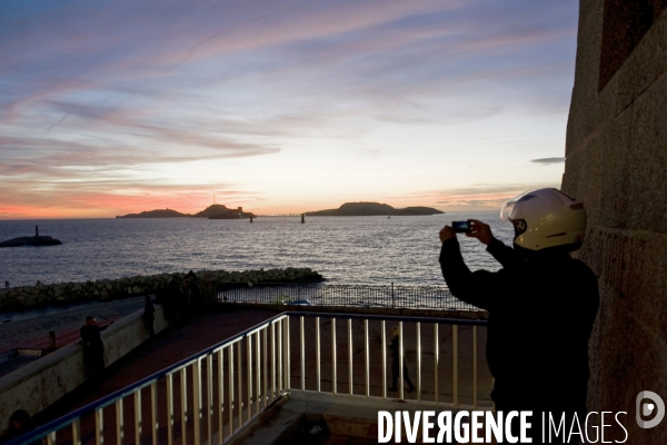 Marseille.De la corniche,un motard photographie le coucher du soleil sur les îles du Frioul.