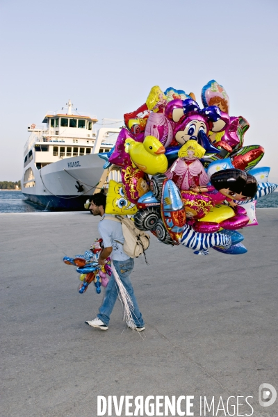Ports illustration.Un marchand de ballons gonfables sur un quai, au démarquement des ferries a Evia en Grece