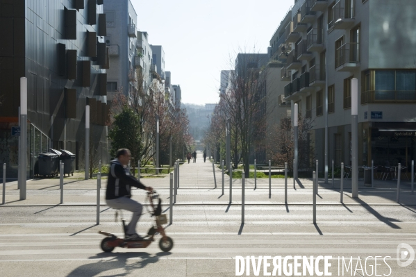 Illustration Mars 2014.Un homme assis sur une patinette electrique traverse une rue du quartier du Trapeze Renault-Rives de Sein