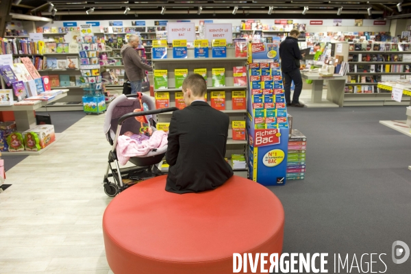 Le Havre.Un jeune pere de famille surveille son enfant dans une poussette dans une librairie