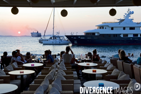 Grece. Ete 2014.Cafe sur le port de Naxos. Au coucher du soleil un ferry quitte le port