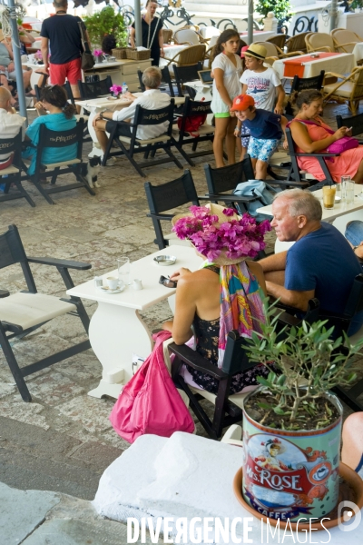 Grece. Ete 2014.Hydra.A la terrasse d un café sur le port, un couple tres chic.Madame porte un chapeau a fleurs de bougainvillier.So chic !