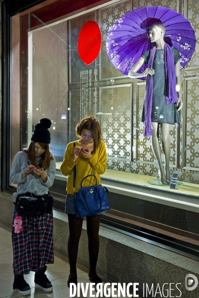Osaka.Mode et fashionistas.Deux jeunes filles consultent leur mobile sur l avenue Mido-suji, les Champs Elysées de la ville.