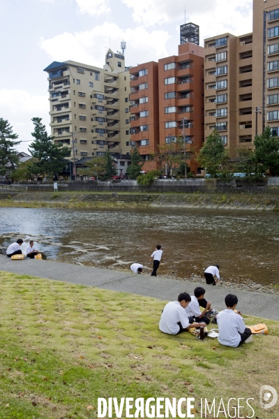Kanazawa.Un groupe d ecoliers dejeunent le long de la riviere Asano, d autres tentent des ricochets