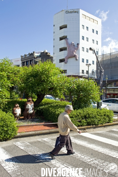 Japon. Tokushima.Un homme passe devant une sculpture de ratons laveurs et de King Kong escaladant la facade d un immeuble.