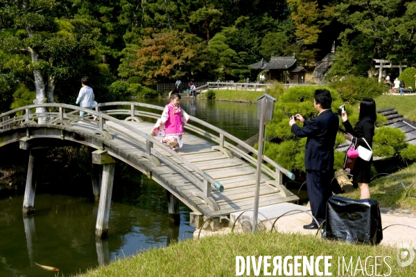 Japon. Okayama.Au le Koraku-en, l un des plus beaux jardins du Japon.Un couple fait des photos de leurs enfants sur un pont