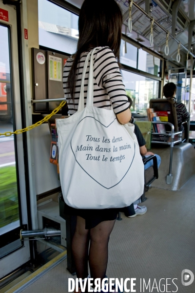 Japon. Okayama..Dans la bus un jeunne femme porte un cabas avec une phrase ecrite en francais-Tous les deux main dans la main, Tout le temps.