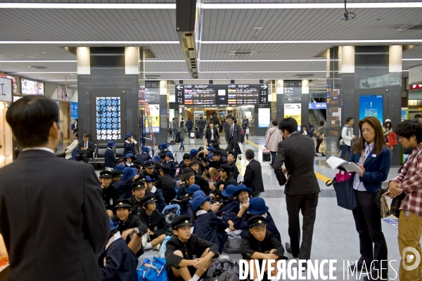 Japon. Okayama. Ecoliers assis par terre dans la gare centrale