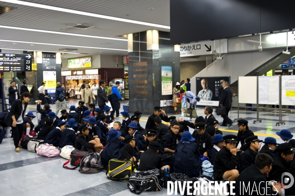 Japon. Okayama. Ecoliers assis par terre dans la gare centrale