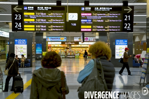 Japon. Okayama.Touristes occidenatux devant le tableau electronique des departs des trains à la gare