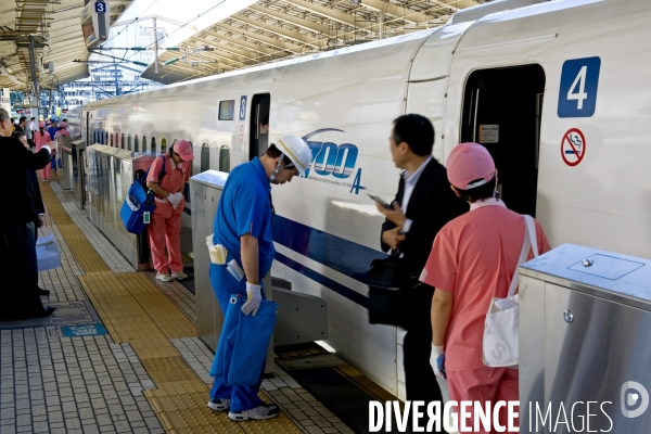 Tokyo. Un Sinkansen a quai en gare centrale.Une brigade de nettoyage, les femmes en uniforme rose, les hommes en bleu attendent que le passargers soient descendus avant de monter a bord et de proceder au nettoyage de la rame.