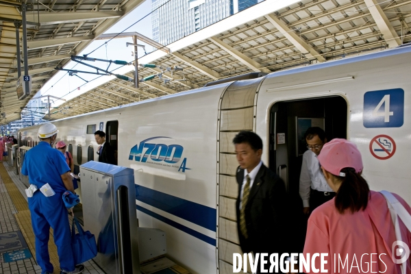 Tokyo. Un Sinkansen a quai en gare centrale.Une brigade de nettoyage, les femmes en uniforme rose, les hommes en bleu attendent que le passargers soient descendus avant de monter a bord et de proceder au nettoyage de la rame.
