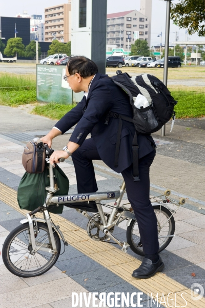 Takamatsu. Un homme d affaires sur son velo pliable de la marque Peugeot.