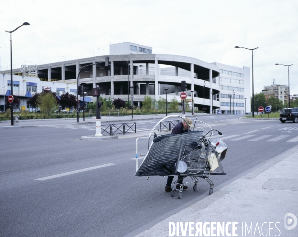 Homme poussant un caddie chargé de ferraille.