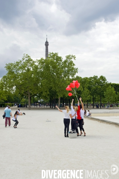 Illustration Mai 2015.Au champ de Mars, des jeunes filles se prennent en photo avec des ballons de couleur rouge en forme de coeur.