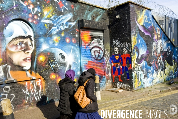 Londres.Devant un mur peint de Brick lane, deux jeune filles en hijab