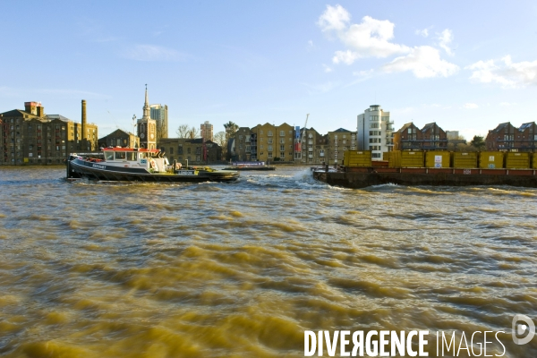 Londres.Sur la Tamise, un remorqueur tire une barge avec des conteneurs