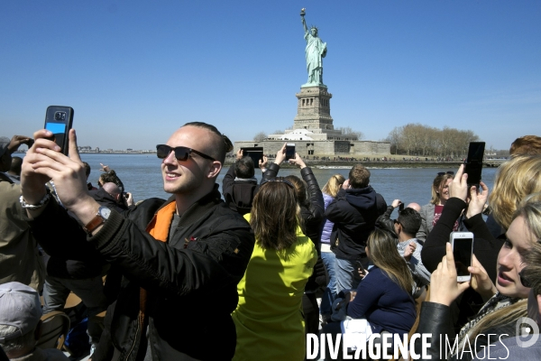Retour a Manhattan # 01.A bord d un bateau de la Circle line, des touristes prennent en photo la Statue de la Liberte