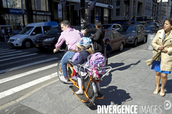 Retour a Manhattan # 01.Au feu rouge,un pere de famille ramene ses filles de l ecole sur un velo et attend son tour au feu rouge